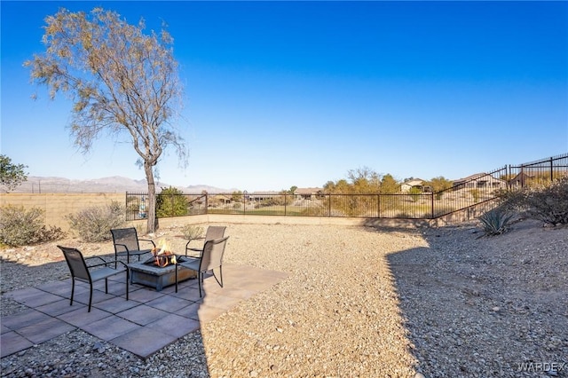 view of yard with an outdoor fire pit, a fenced backyard, and a mountain view