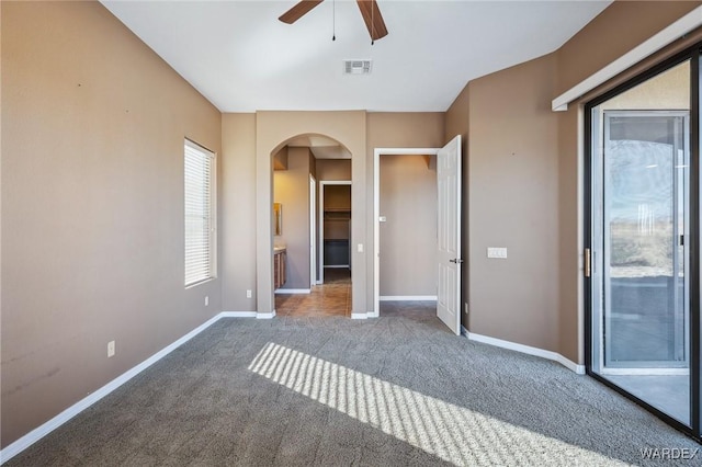 unfurnished bedroom with baseboards, visible vents, arched walkways, access to outside, and carpet floors