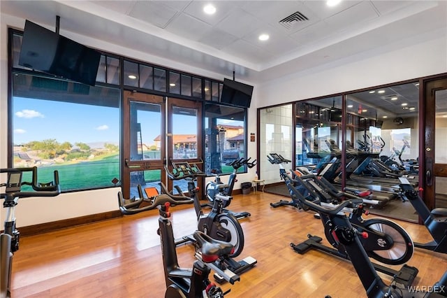 gym with baseboards, visible vents, and wood finished floors