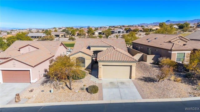 view of front of home featuring driveway, a tile roof, a residential view, an attached garage, and stucco siding