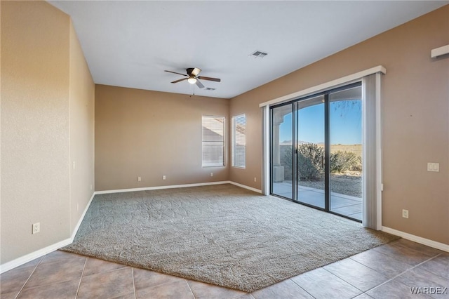 spare room with light tile patterned floors, visible vents, baseboards, light colored carpet, and ceiling fan