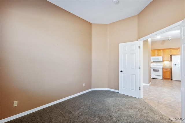 unfurnished room with light carpet, light tile patterned flooring, and baseboards