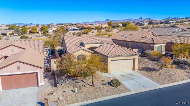 view of front of property featuring concrete driveway, a residential view, a tiled roof, an attached garage, and a mountain view