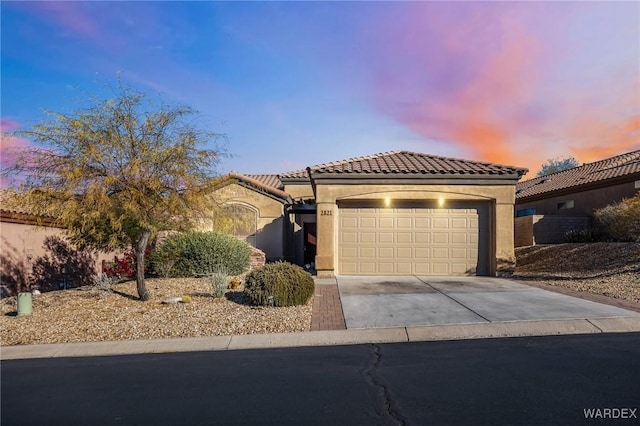 mediterranean / spanish-style home featuring a garage, concrete driveway, a tile roof, and stucco siding