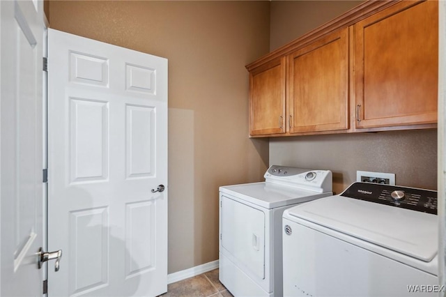 laundry area featuring baseboards, light tile patterned floors, cabinet space, and washer and dryer