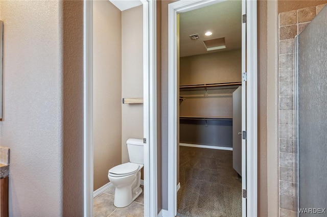 full bathroom featuring toilet, visible vents, a spacious closet, tile patterned floors, and a stall shower