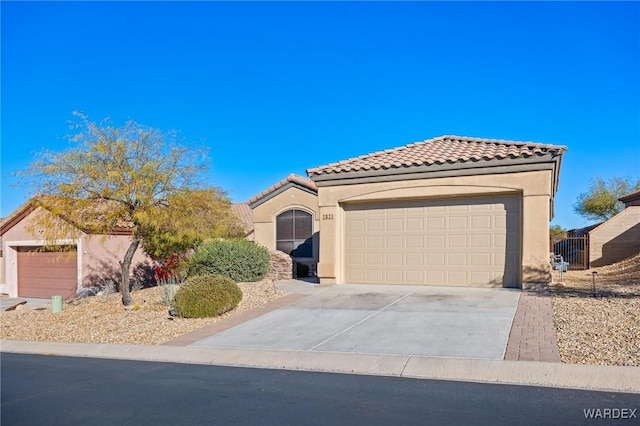 mediterranean / spanish house with concrete driveway, a tiled roof, an attached garage, and stucco siding