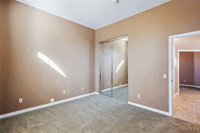 unfurnished bedroom with a closet, carpet, and baseboards