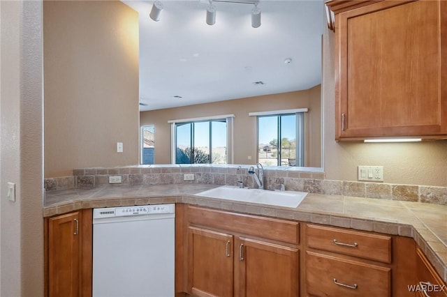 kitchen featuring tile countertops, white dishwasher, brown cabinetry, and a sink