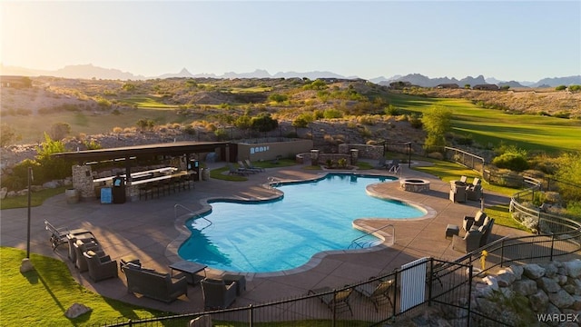 community pool with fence, a mountain view, outdoor dry bar, and a patio