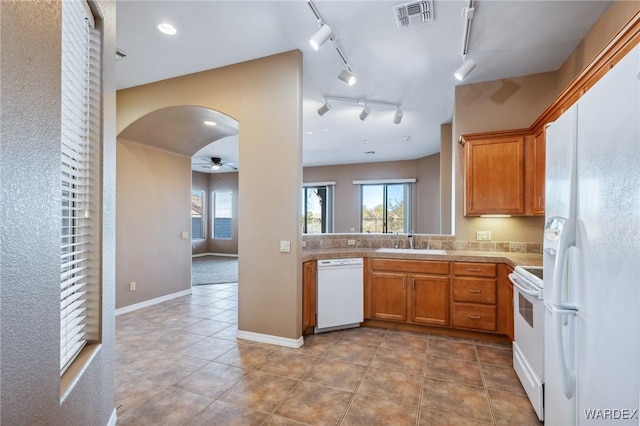 kitchen with white appliances, arched walkways, visible vents, light countertops, and a sink