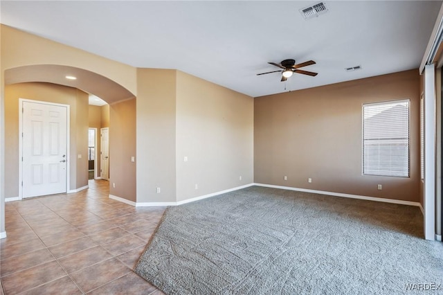 spare room featuring arched walkways, ceiling fan, visible vents, and baseboards