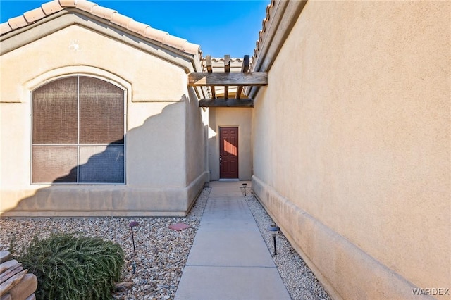 entrance to property featuring stucco siding and a tiled roof