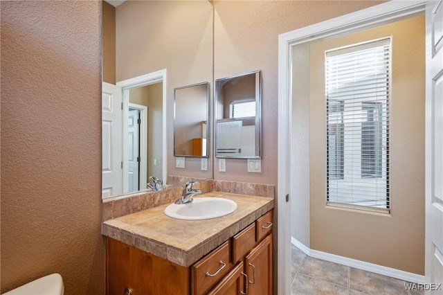 half bath with tile patterned flooring, vanity, and baseboards