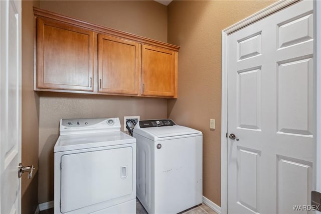 washroom with washer and dryer, cabinet space, and baseboards