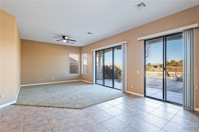 spare room featuring ceiling fan, light tile patterned floors, light colored carpet, visible vents, and baseboards