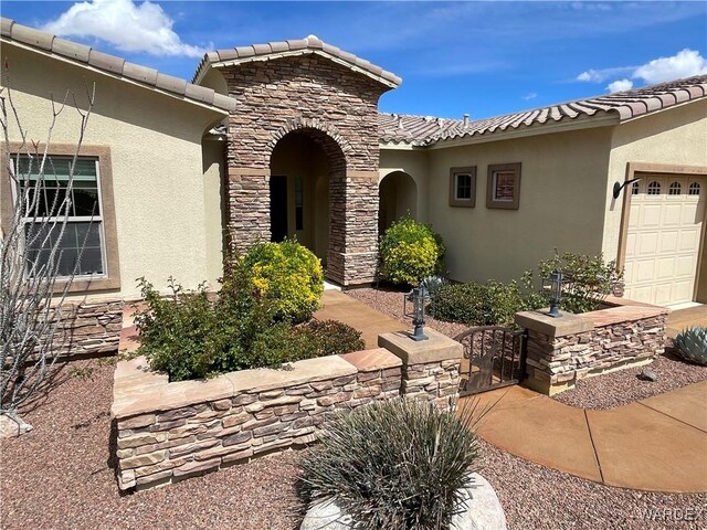 view of front of property with a garage, stone siding, a tile roof, and stucco siding