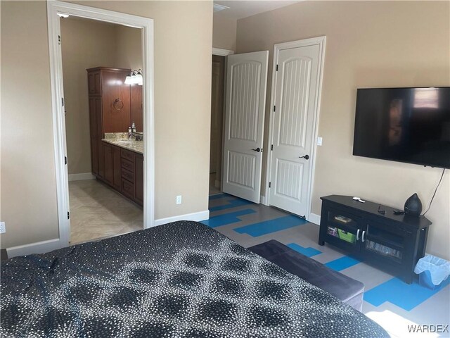 bedroom with baseboards, a sink, and ensuite bathroom