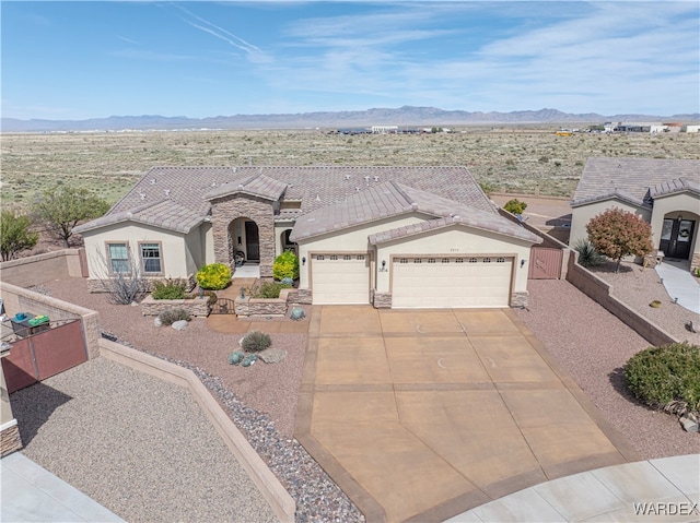 french provincial home featuring stucco siding, an attached garage, a mountain view, stone siding, and driveway