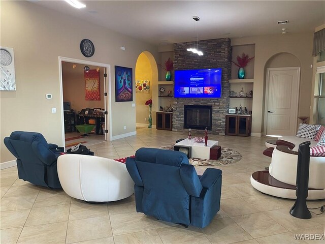 living area with arched walkways, light tile patterned floors, a large fireplace, visible vents, and baseboards