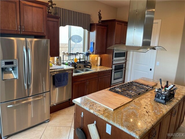 kitchen featuring light tile patterned floors, a center island, light stone countertops, range hood, and stainless steel appliances