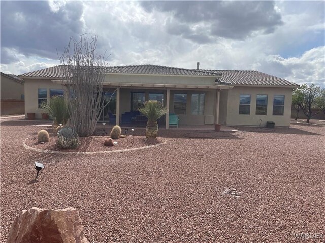 back of property featuring a patio, a tile roof, and stucco siding