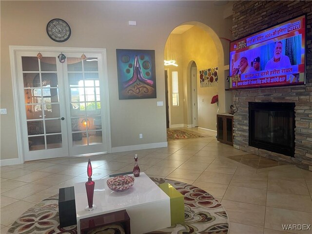 living room featuring a stone fireplace, baseboards, and tile patterned floors