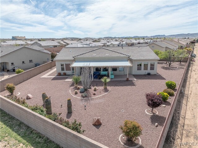 view of front of home with a fenced backyard, a tiled roof, a residential view, stucco siding, and a patio area