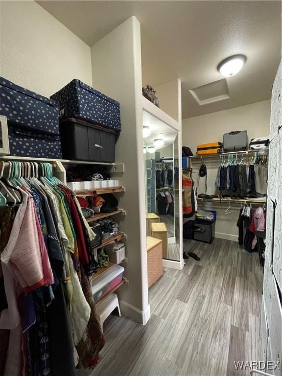 spacious closet featuring attic access and wood finished floors