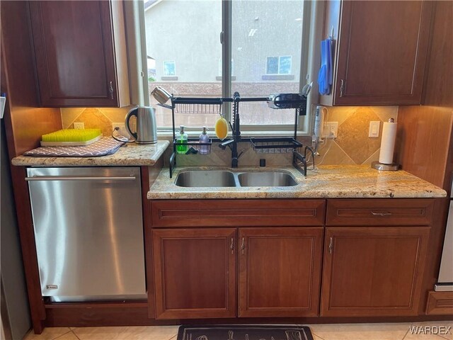 kitchen featuring dishwasher, light stone counters, backsplash, and a sink