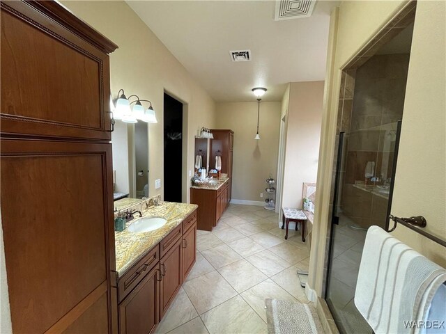 full bath featuring two vanities, a stall shower, visible vents, and a sink