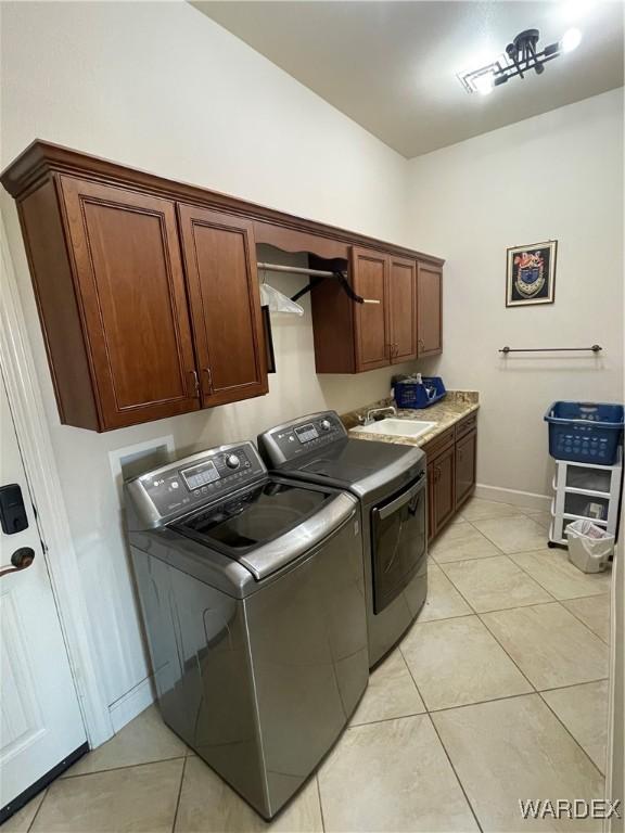 clothes washing area featuring cabinet space, light tile patterned floors, a sink, and independent washer and dryer