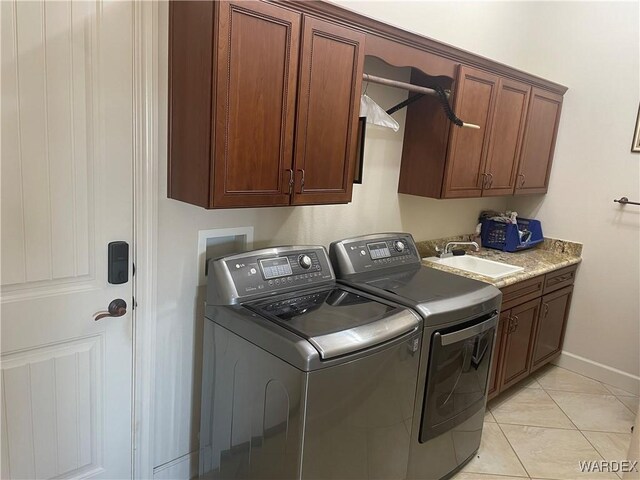 washroom featuring cabinet space, baseboards, a sink, and washing machine and clothes dryer