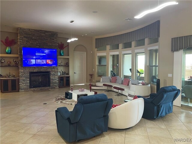 living room with a towering ceiling, a fireplace, and light tile patterned flooring