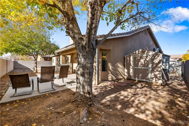 exterior space featuring an outbuilding, stucco siding, a storage unit, a patio area, and a fenced backyard