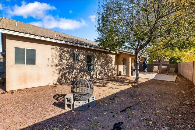 back of property with a fire pit, a patio, a fenced backyard, a tiled roof, and stucco siding