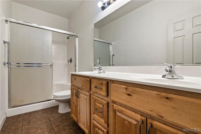 bathroom with double vanity, a sink, toilet, and tile patterned floors