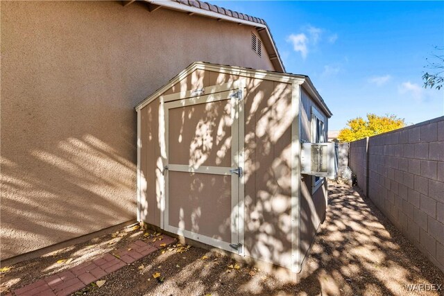 exterior space featuring a tile roof, fence, an outdoor structure, a shed, and stucco siding