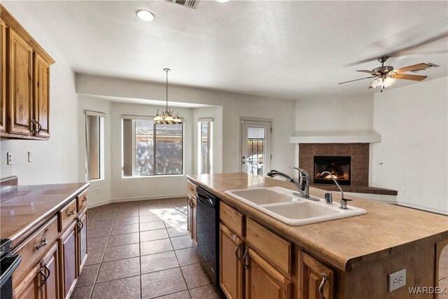 kitchen with black dishwasher, an island with sink, a sink, and a wealth of natural light