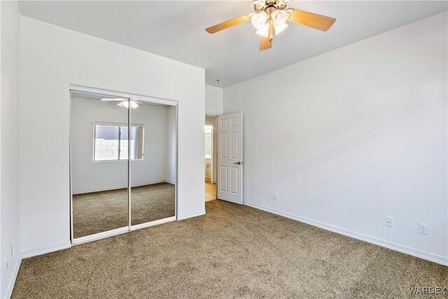 unfurnished bedroom featuring carpet floors, a ceiling fan, baseboards, and a closet