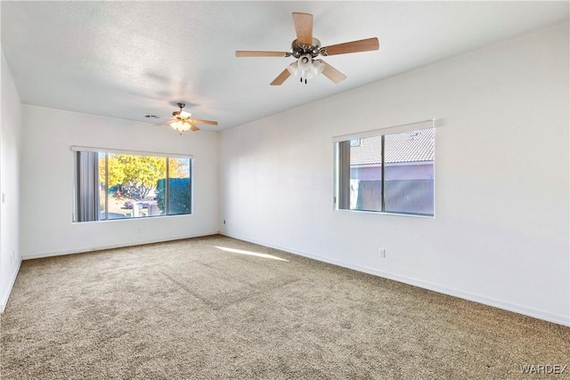 unfurnished room with a textured ceiling, carpet floors, a ceiling fan, and baseboards