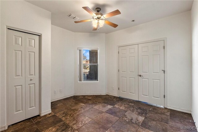 unfurnished bedroom featuring baseboards, visible vents, a ceiling fan, and stone finish flooring