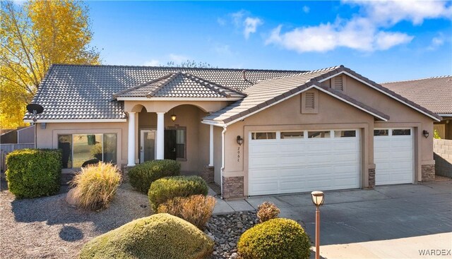 view of front of property featuring a garage, driveway, a tile roof, and stucco siding