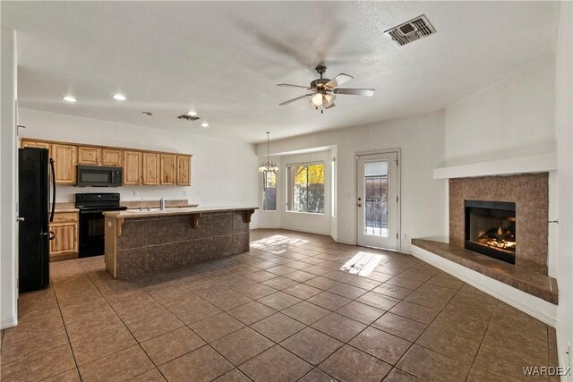 kitchen with visible vents, open floor plan, a kitchen breakfast bar, light countertops, and black appliances