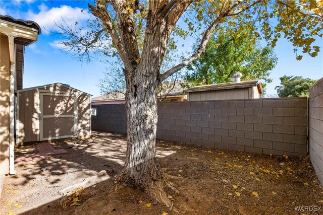 view of yard with a fenced backyard, a storage unit, and an outdoor structure