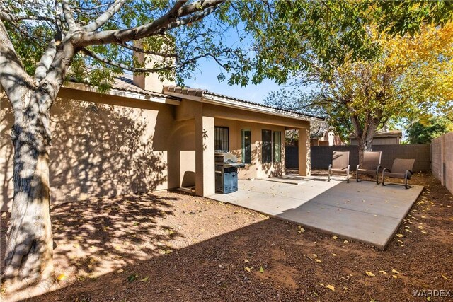 rear view of property with stucco siding, a fenced backyard, a tile roof, and a patio