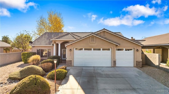 view of front facade with concrete driveway, stone siding, an attached garage, fence, and stucco siding