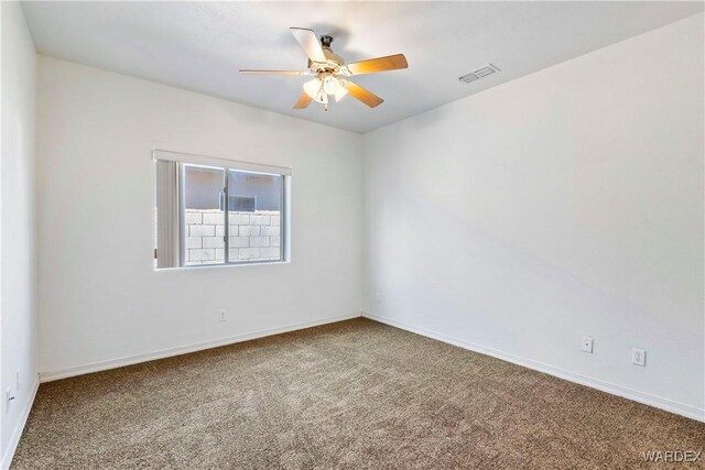 carpeted empty room featuring ceiling fan, visible vents, and baseboards