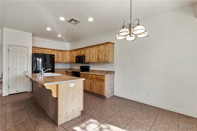 kitchen featuring visible vents, light countertops, a sink, an island with sink, and black appliances