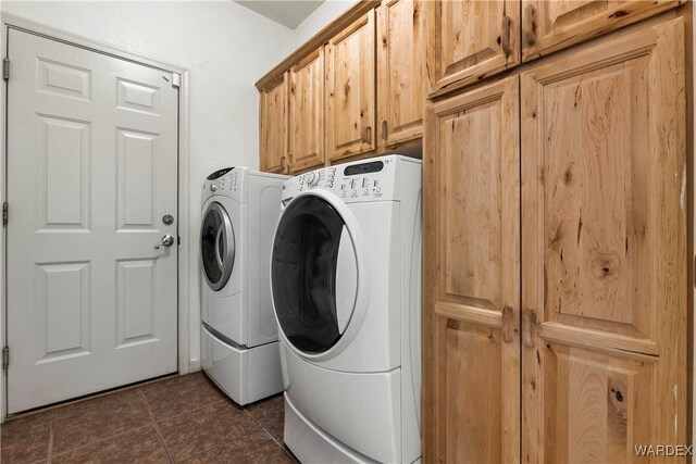 laundry area with cabinet space, dark tile patterned floors, and independent washer and dryer